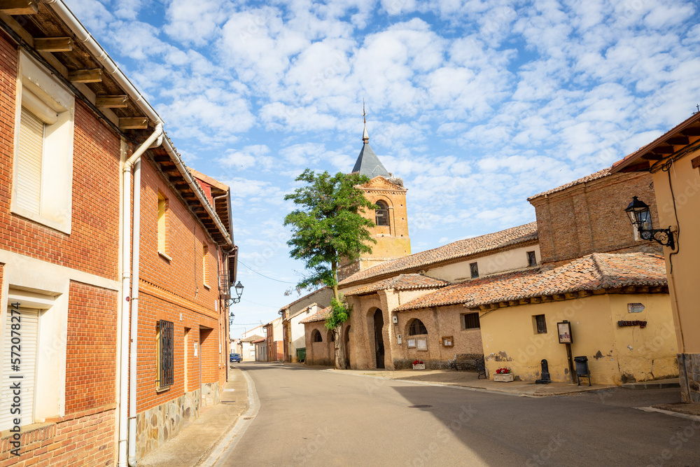 street in El Burgo Ranero village with the church of Saint Peter the Apostle in the center, province of Leon, Castile and Leon, Spain - June 2022