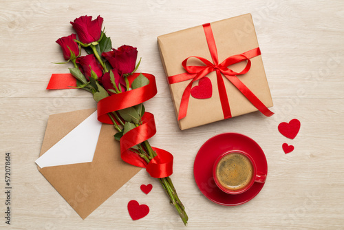 Red cup of coffee with roses on wooden background, top view