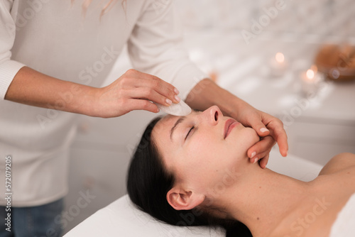 Professional massage therapist applying face massage to client