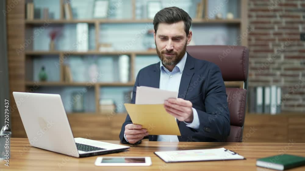 Happy business man investor received opening envelope mail letter with great news with project work investment success or salary increase Excited entrepreneur celebrating victory at workplace indoors Happy business man investor received opening envelope mail letter with great news with project work investment success or salary increase Excited entrepreneur celebrating victory at workplace indoors
