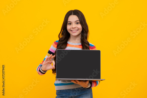 Young student school girl, studying with laptop computer. E-learning concept. Screen of laptop computer with copy space mock up. Happy teenager, positive and smiling emotions of teen schoolgirl.