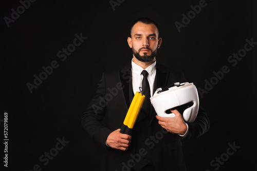 Serious man wearing black suit is holding nunchaku and a protection helemet. photo