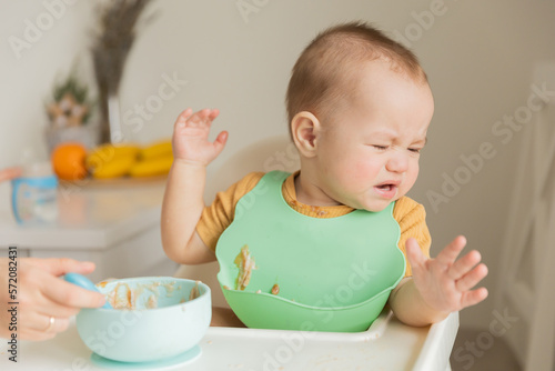 Obraz na płótnie a child of 1 year is naughty at the table, does not want to eat