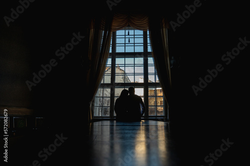 backlight of people near the window  the figure of young people near a large ancient window