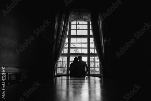 backlight of people near the window, the figure of young people near a large ancient window. Black and white photo