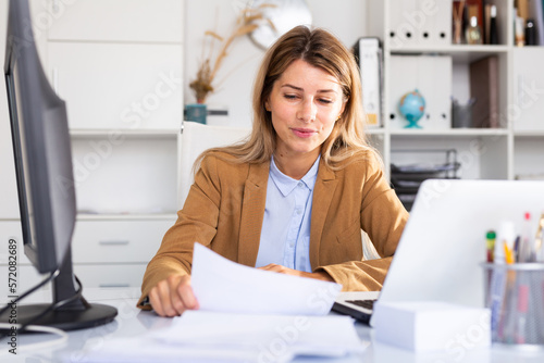 Woman working with papers and laptop in office