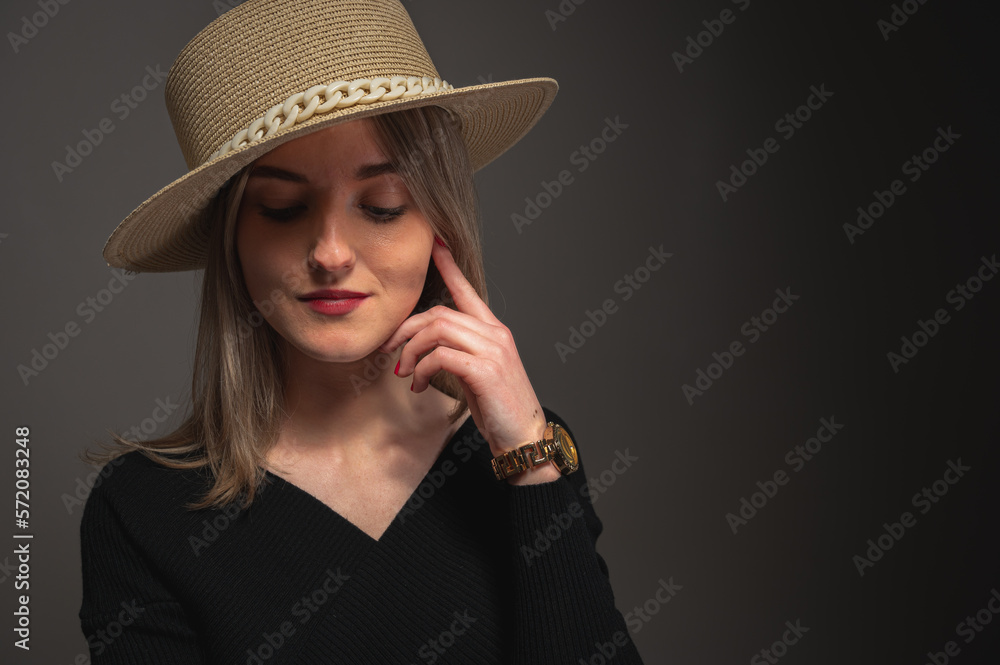 young, pretty girl with a straw hat, on a gray background. Emotions and modesty, looking down young, pretty girl with a straw hat, on a gray background. Emotions and modesty, looking down