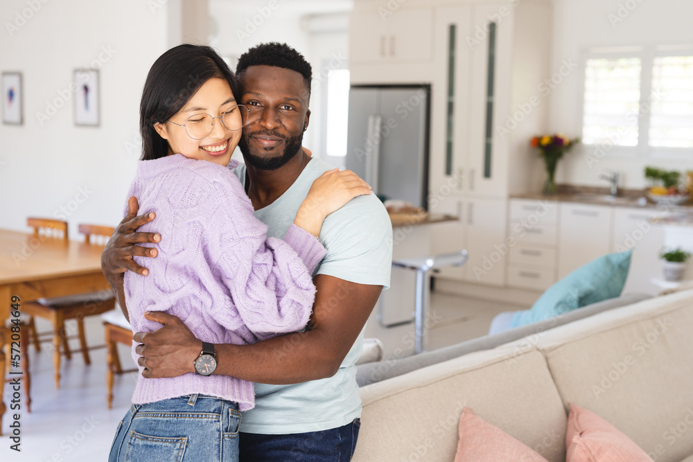 Portrait of happy diverse couple embracing in living room Portrait of happy diverse couple embracing in living room