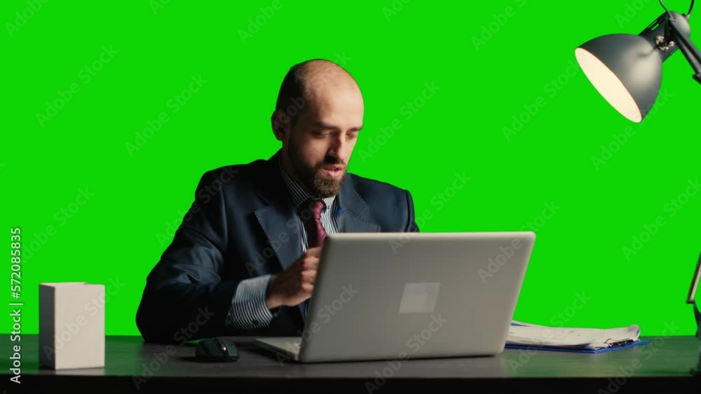 Team leader analyzing papers sitting over green screen, working with laptop and taking notes on papers. Caucasian businessman posing over isolated mockup backdrop, chroma key space. Team leader analyzing papers sitting over green screen, working with laptop and taking notes on papers. Caucasian businessman posing over isolated mockup backdrop, chroma key space.
