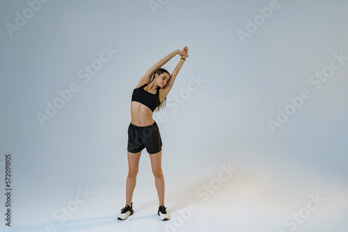 Sporty woman doing warm-up before training session in gym on studio background. High quality photo