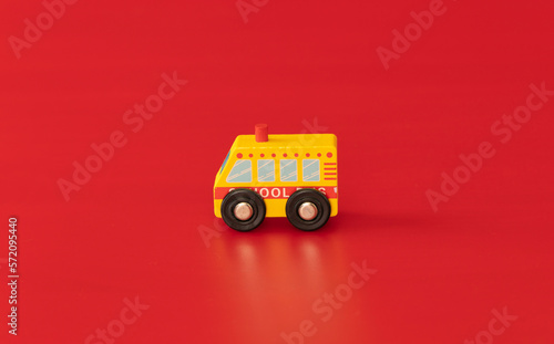 Wood toy for kids: School bus isolated on red background. Service for kids and young people.