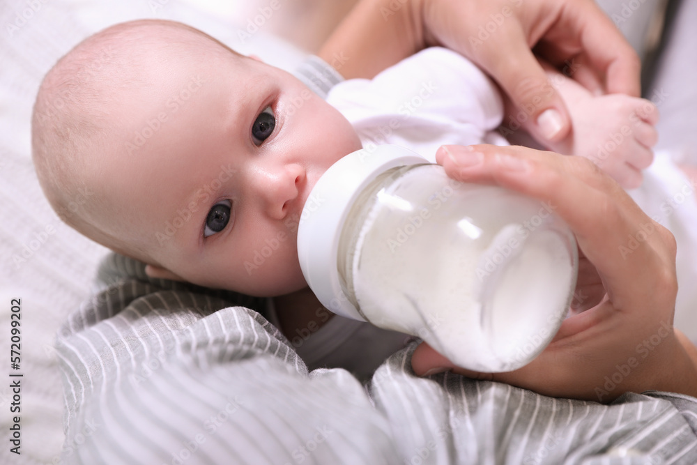 Mother feeding her little baby from bottle, closeup Mother feeding her little baby from bottle, closeup