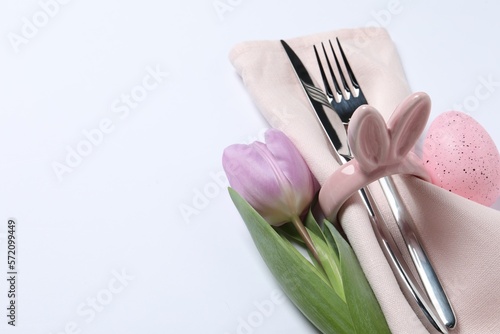 Cutlery set  Easter egg and tulip on white background  space for text. Festive table setting