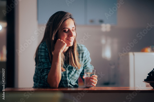 Woman Waking up During Nighttime to Drink a Glass of Water. Happy lady feeling thirsty in the middle of the night 
