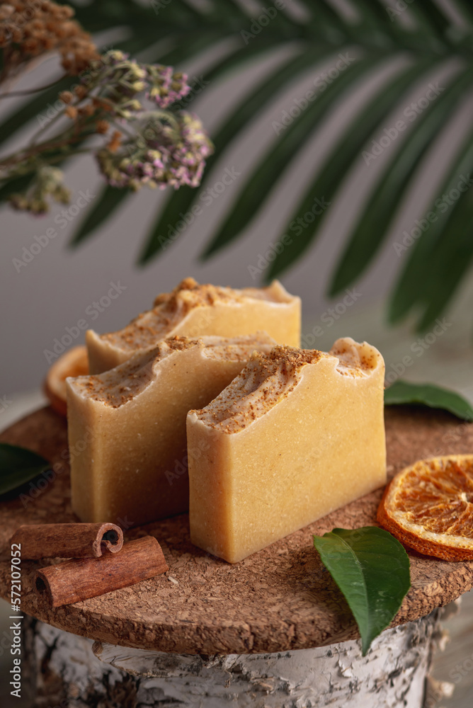 Piece of natural soap and slices of oranges, cinnamon and green leaves on the wooden table. Concept of eco soap and interesting hobby Piece of natural soap and slices of oranges, cinnamon and green leaves on the wooden table. Concept of eco soap and interesting hobby