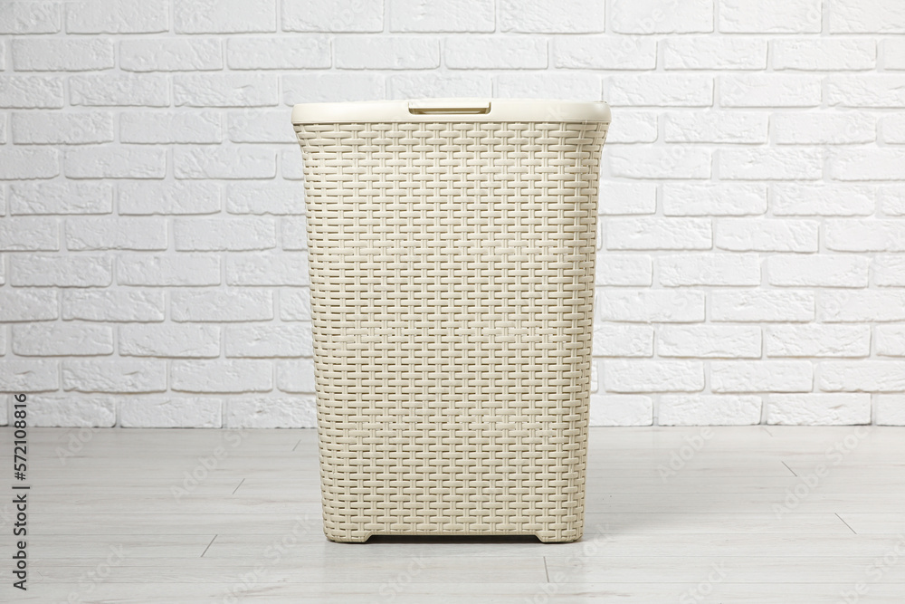 Empty laundry basket near white brick wall Stock Photo Adobe Stock