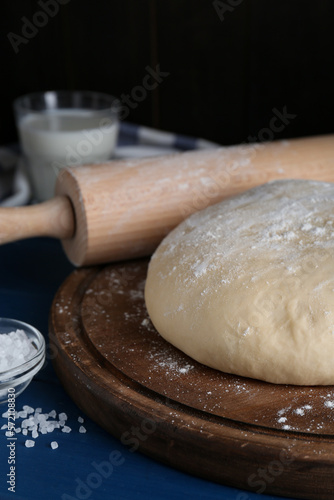 Fresh yeast dough with flour on blue wooden table, closeup