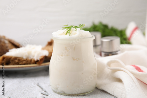 Delicious pork lard with dill in glass jar on light textured table, closeup photo