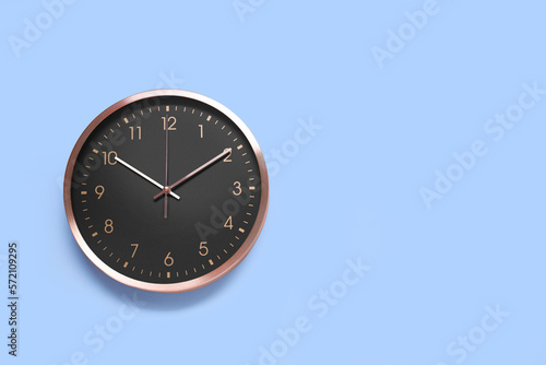 Stylish round clock on light blue background, top view with space for text. Interior element