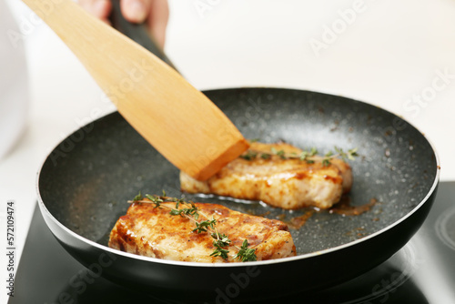 Chef cooking delicious meat with thyme in frying pan indoors, closeup