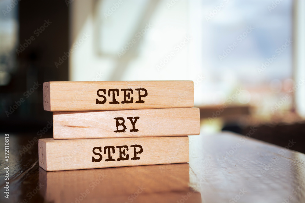 Wooden blocks with words 'step by step'. Wooden blocks with words 'step by step'.