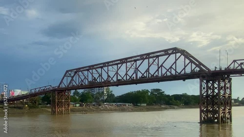 Distinctive Truss Suspended Bridge Over Quiet River Under Blue Sky, Sylhet, Bangladesh photo