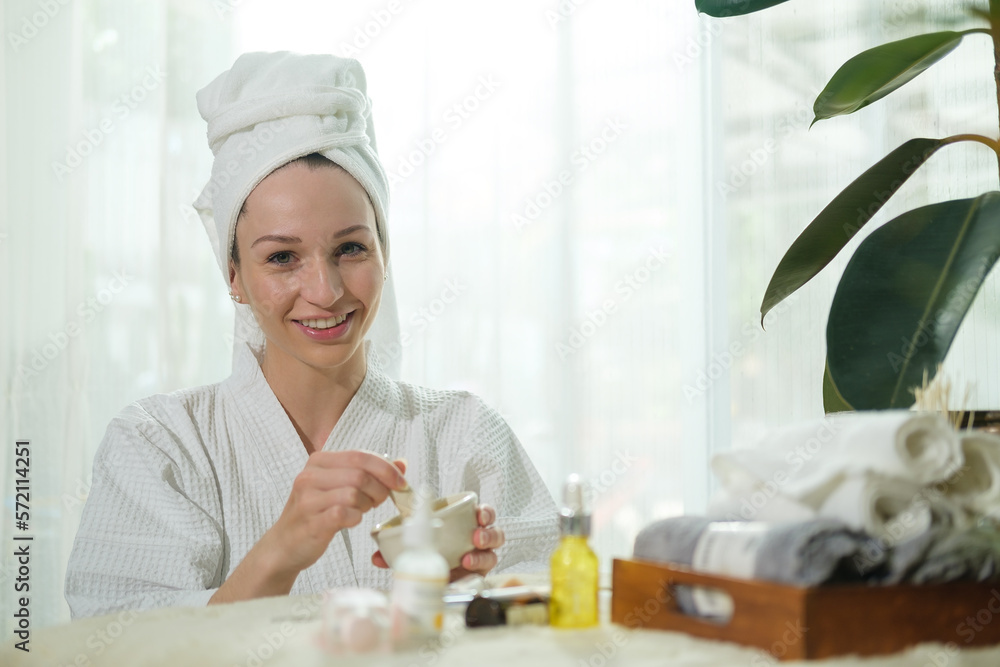 Portrait of caucasian woman in bathrobe making homemade turmeric face mask in bowl. Facial spa treatment concept. Portrait of caucasian woman in bathrobe making homemade turmeric face mask in bowl. Facial spa treatment concept.