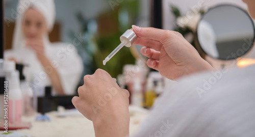 Close up view of woman dropping moisturizing serum on her hand. Beauty therapy, skincare concept.