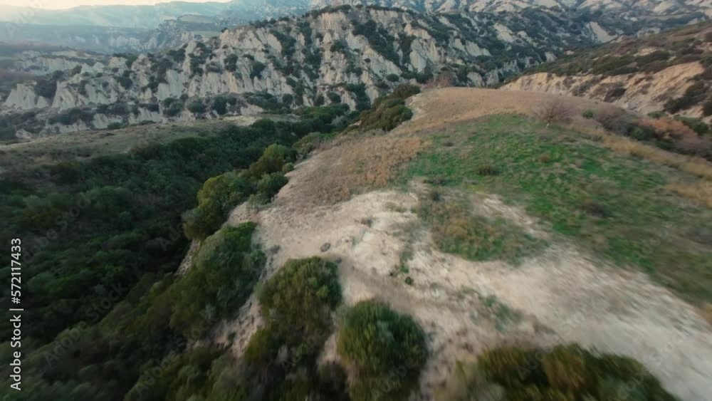 Fast FPV cruising drone shot over the hilly landscape of Calanchi di Aliano in Italy during sunset. Fast FPV cruising drone shot over the hilly landscape of Calanchi di Aliano in Italy during sunset.