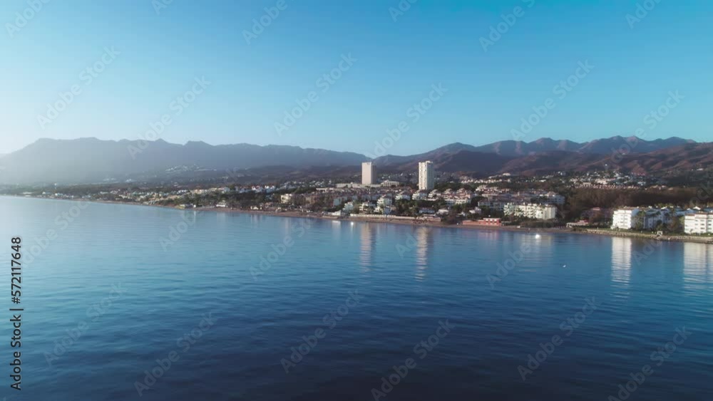 Aerial over the coastline of Cabopino, Marbella, Spain. Moving closer to the coastline on with a clear blue sky Aerial over the coastline of Cabopino, Marbella, Spain. Moving closer to the coastline on with a clear blue sky