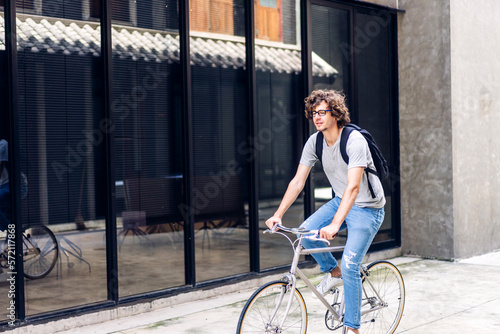 Portrait of casual hipster handsome businessman with backpack looking forward while commuting riding bicycle on the street city way go to work.business travel transport bike concept