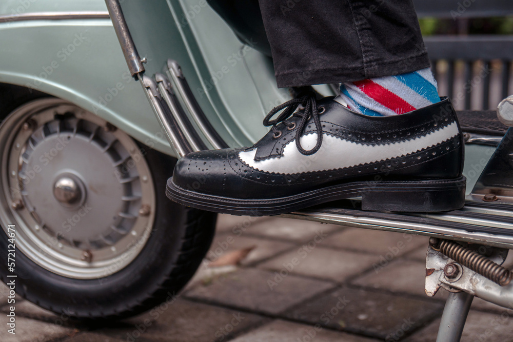 These hand-made black-and-white wingtip shoes with loafers sole made from genuine leather are being worn to hang out with an old green scooter These hand-made black-and-white wingtip shoes with loafers sole made from genuine leather are being worn to hang out with an old green scooter