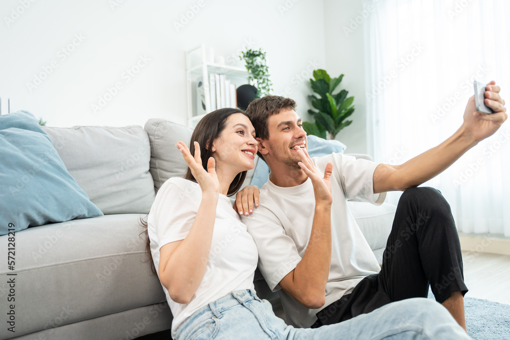 Caucasian attractive couple use mobile phone video call in living room Caucasian attractive couple use mobile phone video call in living room