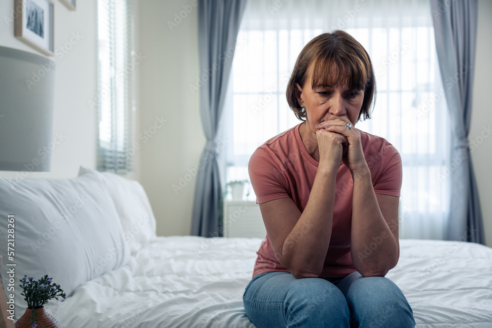 Caucasian mature woman frustrating while sit alone on bed in bedroom. Caucasian mature woman frustrating while sit alone on bed in bedroom.
