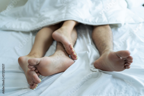 Close up feet of young couple starting foreplay and making love on bed