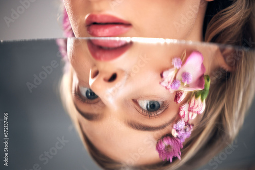 Beauty  mirror face and model with flower product  sustainable agriculture and natural skincare reflection. Facial makeup  nature plant cosmetics and eco friendly woman isolated on studio background