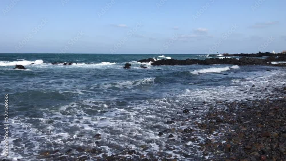 제주도 몽돌해변 알작지 푸른바다에서 하얀파도가 밀려와 현무암에 부딪혀 부서지는 영상