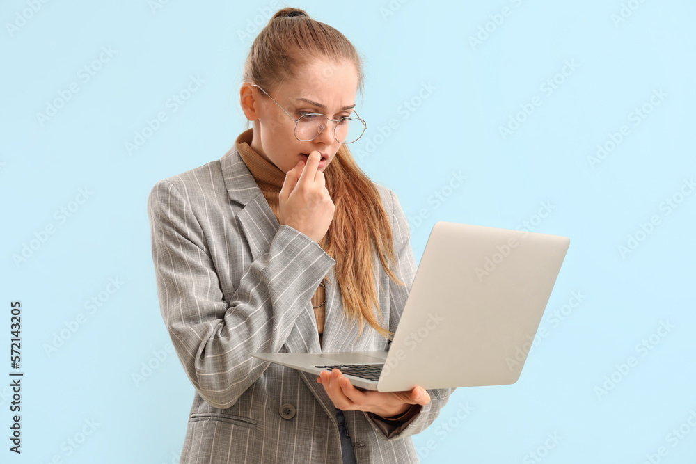 Young businesswoman with laptop biting nails on blue background Young businesswoman with laptop biting nails on blue background