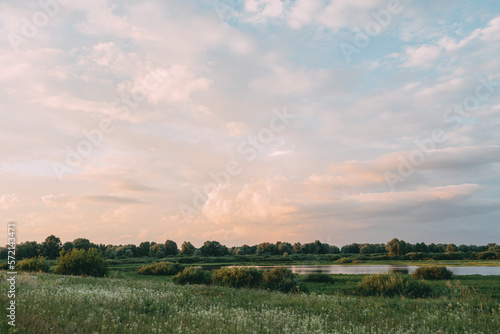 Beautiful natural panoramic countryside landscape. Green field with lake under endless sky. Pastel colours background