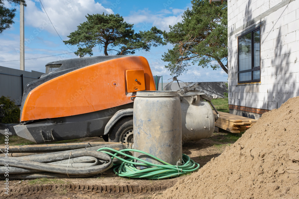 A machine with a mixer is an installation for feeding cement mixture for pouring semi-dry floor screed in the house. Construction site with a slide of sand, preparation for leveling the rough floor of A machine with a mixer is an installation for feeding cement mixture for pouring semi-dry floor screed in the house. Construction site with a slide of sand, preparation for leveling the rough floor of