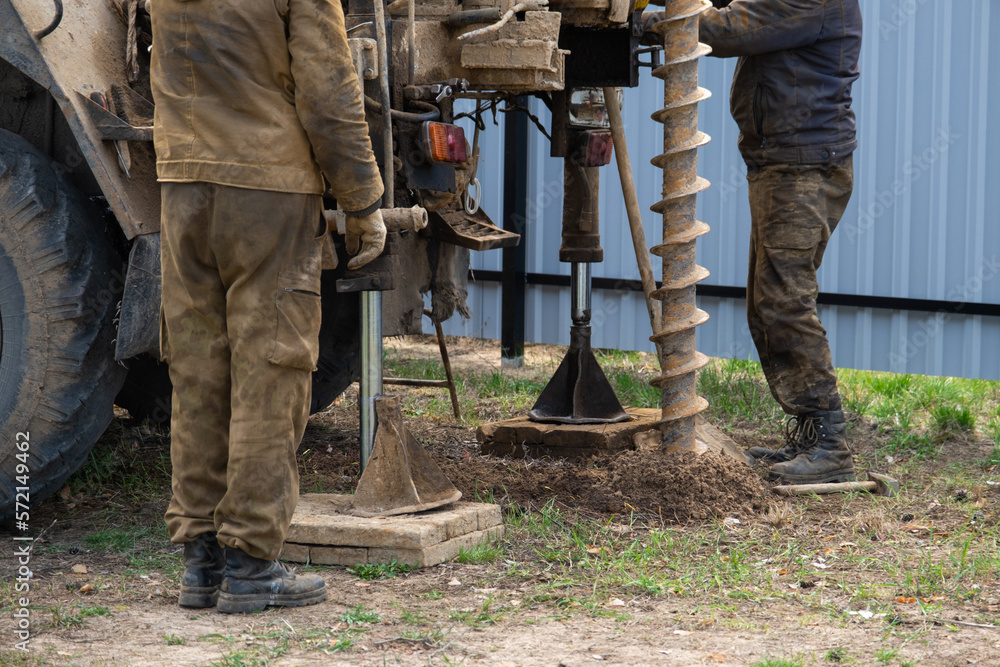 Team of workers with drilling rig on car are drilling artesian well for