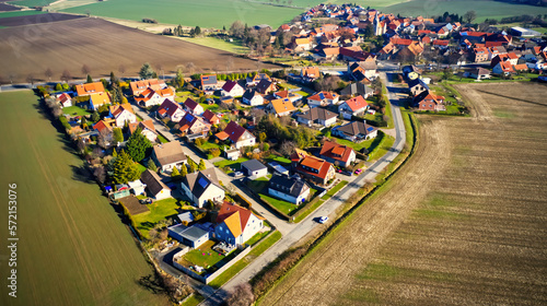 Aerial view from the edge of a small German village beetween fields and meadows with family houses and small gardens © Frank