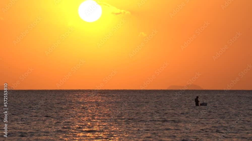 Silhouette fisherman looking for fish in the sea at dusk and sunset time. The sun is shining round. Silhouette fisherman looking for fish in the sea at dusk and sunset time. The sun is shining round.