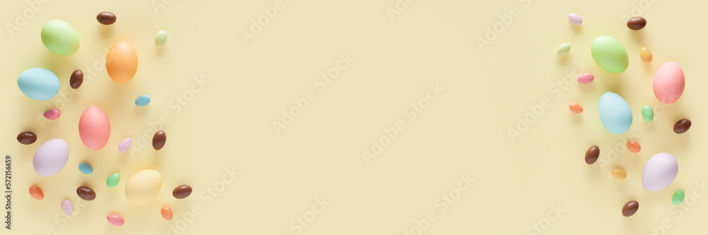 Happy Easter banner. Colorful Easter eggs and candies on the yellow background. Top view. Copy space.