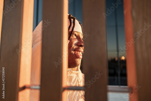 happy african american man smiling at sunset over the city. - view through a fence -