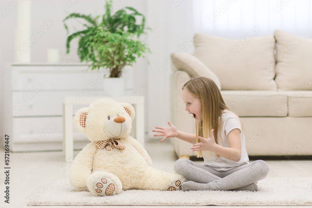 Photo of little blond girl talking to her white teddy bear. Photo of little blond girl talking to her white teddy bear.