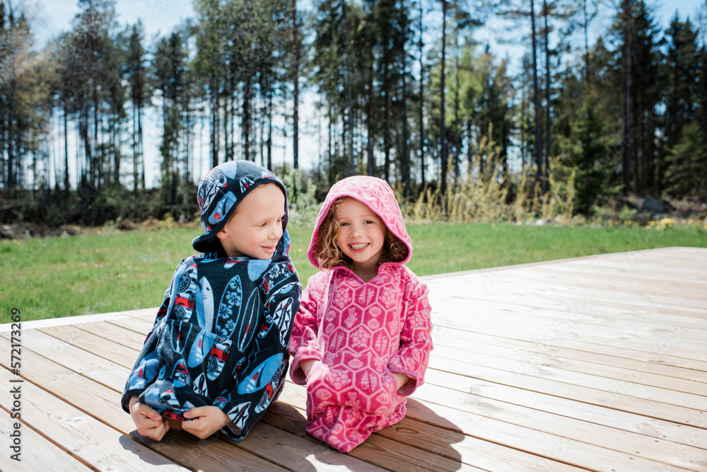 portrait of a girl and boy sat in their towels after swimming at home portrait of a girl and boy sat in their towels after swimming at home