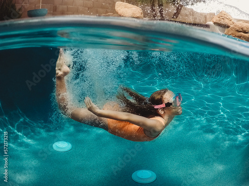 Girl swimming under water in pool photo