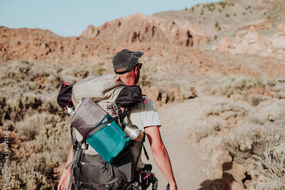 A hiker walking with his backpack in Guajara mountain, El Teide A hiker walking with his backpack in Guajara mountain, El Teide