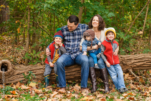 portrait of a family sitting together in a wooded park photo